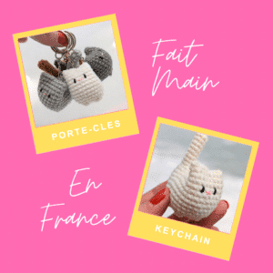 Plusieurs porte-clés en forme de chat crochetés, de couleurs variées, dont blanc, gris et noir. Chaque porte-clés présente un petit corps rond, des oreilles dressées et un nez rose.